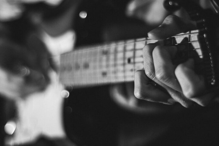 Black-and-white close-up of hands playing an electric guitar